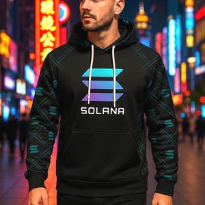 Peut inclure: Un sweat à capuche noir avec le logo Solana en bleu, violet et blanc. Le sweat à capuche a une capuche à cordon et une poche avant. Les manches ont un motif géométrique teal et noir. Le mot "SOLANA" est imprimé en lettres blanches.