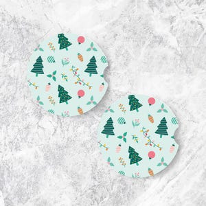 May include: Two round car coasters with a light blue background and a repeating Christmas pattern. The pattern includes green Christmas trees, red ornaments, and strings of lights. The coasters have a small notch for easy removal.