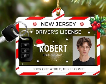 May include: A rectangular Christmas ornament shaped like a New Jersey driver's license with a red and white candy cane border, a photo of a person, the name Robert, the text Issued: 2025, and Look out world, here I come, with a key fob attached.