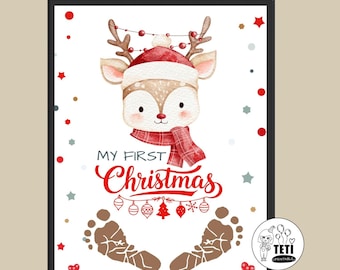 May include: A framed print featuring a watercolor illustration of a reindeer wearing a Santa hat and scarf. The text "MY FIRST Christmas" is in red script, with baby footprints below. Red and white accents surround the image.