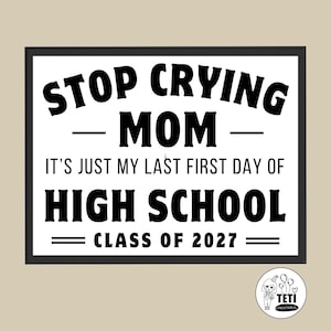 以下が含まれることがあります： 黒い枠と白い背景の長方形の看板で、黒い文字で「STOP CRYING MOM, IT'S JUST MY LAST FIRST DAY OF HIGH SCHOOL, CLASS OF 2027」と書かれています。隅にはキャラクターと風船が描かれた小さな円形のロゴがあります。