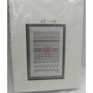 May include: A framed cross-stitch sampler with various stitch patterns in red, blue, and gray. The frame measures 3 1/8" x 4 3/4". The bottom of the sampler has the text "DC 1989".