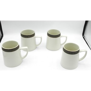 May include: Four white ceramic mugs with a dark brown band around the rim. Each mug has a white handle. The mugs are arranged on a white surface.