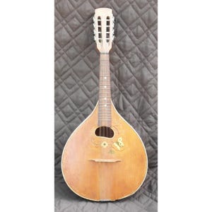 May include: A vintage mandolin with a light brown wooden body and neck. The instrument features a rounded body, a sound hole, and a decorative floral design. The headstock has tuning pegs. The mandolin is a stringed instrument.