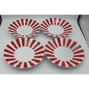 May include: Four white ceramic plates with a red striped design radiating from the center. The plates are arranged in a square formation, showcasing a clean and modern aesthetic. Ideal for serving meals.