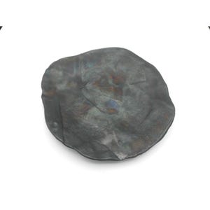 May include: A handcrafted, irregularly shaped, dark gray metal dish. The surface has a textured, mottled appearance with hints of blue and bronze. The dish is likely used for decorative purposes or as a small serving piece.