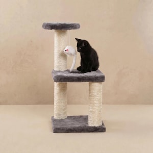 May include: A gray cat tree with a black kitten and a hanging white toy mouse. The cat tree has two platforms with gray plush fabric and rope-wrapped posts. The kitten sits on the top platform, looking at the toy.