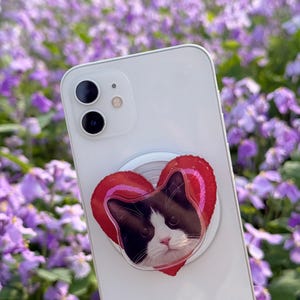 May include: A white ceramic mug with a black handle and the text "But First, Coffee" in a black, handwritten-style font. The mug is on a white surface.