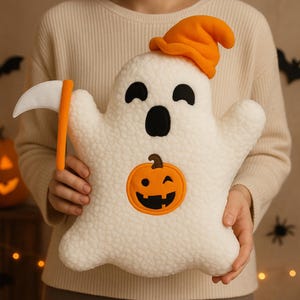 May include: A white plush ghost-shaped pillow with black eyes and mouth, wearing an orange hat. A smiling jack-o'-lantern is on the front. The ghost holds an orange and white scythe. Halloween-themed decorative item.