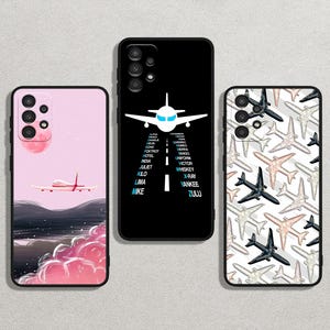 May include: Three phone cases with different designs. The first case is pink with a white airplane and clouds. The second case is black with a white airplane and a list of words. The third case is white with a pattern of black airplanes.