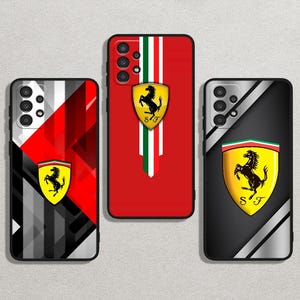 以下が含まれることがあります： フェラーリのロゴが入った3つの携帯電話ケース。1つは白と緑のストライプが入った赤色、もう1つは赤色のデザインが入った黒とグレー、3つ目は黄色のシールドが入った黒色です。