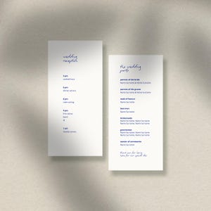 May include: Two white wedding stationery cards with elegant navy blue calligraphy. One card lists the wedding reception schedule, and the other lists the wedding party members. The cards are set against a neutral background.