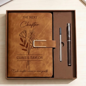 Puede incluir: Un juego de diario de cuero marrón con un bolígrafo y una recarga a juego. La cubierta del diario está grabada con diseños florales y el texto "The Next Chapter" y "Curtis Taylor". El juego se presenta en una caja marrón.