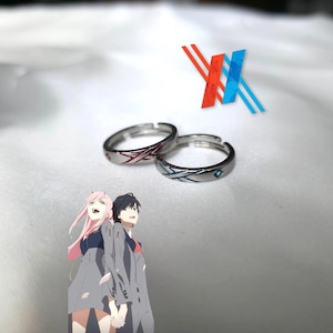 May include: Two silver rings with red and blue enamel designs. The rings are on a white surface with a blue and red X logo in the background.