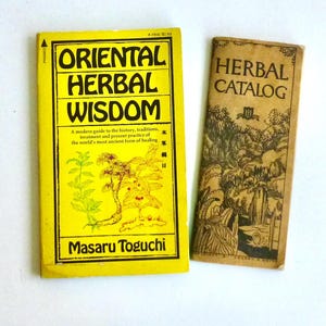 May include: Two vintage books: "Oriental Herbal Wisdom" in yellow with black text and a botanical illustration, and "Herbal Catalog" in brown with a landscape illustration. The first book is by Masaru Toguchi.