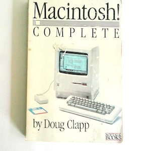 May include: A softcover book titled Macintosh! COMPLETE by Doug Clapp. The white cover features a graphic illustration of a vintage beige Macintosh computer, a keyboard, a mouse, and a blue floppy disk. The Softalk Books logo is at the bottom.