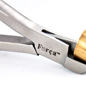 May include: Close-up of a silver jewelry pliers with a brass ring in the jaws. The pliers are labeled "Força™".