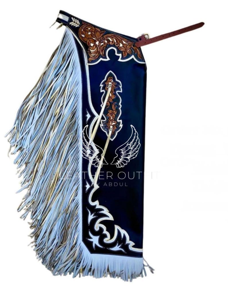 May include: A navy blue leather chaps with intricate brown and white decorative patterns. The chaps feature long, flowing fringe in shades of white and gold. The text "LEATHER OUT" and "ABDUL" is visible.