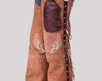 Op de afbeelding: Bruine leren chaps met franjes en decoratieve stiksels. De chaps hebben een donkerbruine leren patch op de dij en een metalen ringdetail. De chaps zijn ontworpen om over een spijkerbroek te worden gedragen.