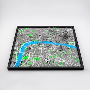 Può includere: Una mappa 3D incorniciata di Londra, con una rappresentazione dettagliata della città. Il Tamigi è evidenziato in blu brillante, con aree verdi che indicano i parchi. La cornice è nera.