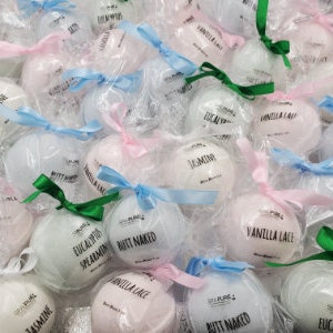 May include: A variety of bath bombs wrapped in clear plastic with colorful ribbons. The bath bombs are labeled with different scents, including Eucalyptus Spearmint, Vanilla Lace, and Butt Naked.