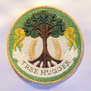 May include: A green, white, and yellow embroidered patch with a tree in the center and the words "Tree Hugger" on a white banner.