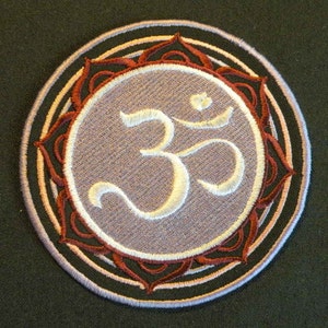 May include: A purple embroidered patch with a white Om symbol surrounded by a red and white mandala design.