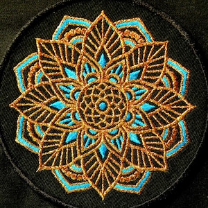 May include: A round embroidered patch with a gold and blue mandala design. The mandala has a circular pattern with intricate details and a flower-like shape.
