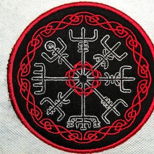 Könnte beinhalten: Ein gestickter schwarzer und roter Aufnäher mit einem weißen Kompass-Design und einem roten keltischen Knotenrand.