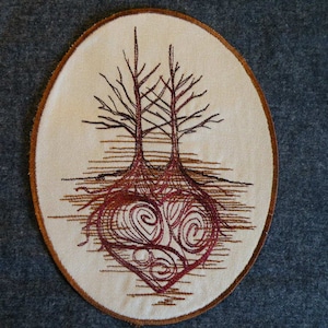 May include: Embroidered patch with a brown oval border. The patch features a white background with two brown trees with intertwined roots forming a heart shape. The heart is filled with a swirling red pattern.