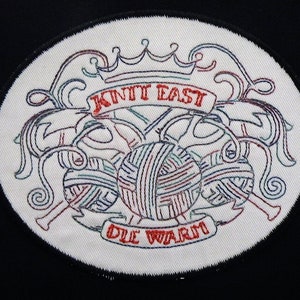 May include: A white oval embroidered patch with a red crown, two yarn balls, and two knitting needles. The text "Knit East" and "Die Wurm" are embroidered in red.