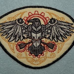 May include: A beige embroidered patch with a black outline, featuring a stylized silver raven with gears and a red and gold design.