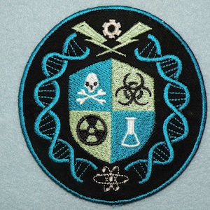 May include: A black and blue embroidered patch with a shield design. The shield is divided into four sections, each with a different symbol: a skull and crossbones, a biohazard symbol, a radiation symbol, and a beaker. The shield is surrounded by a double helix DNA strand and other scientific symbols.