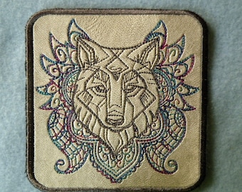 May include: A beige leather patch with a brown border features an embroidered wolf head with intricate, colorful floral designs around it.