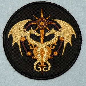 May include: A black embroidered patch with two gold dragons facing each other, with a sunburst design in the center.