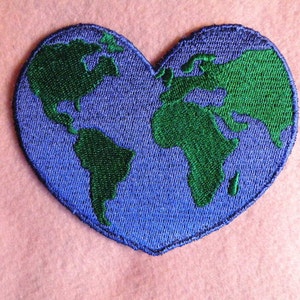 May include: A blue and green embroidered patch shaped like a heart with a world map design.