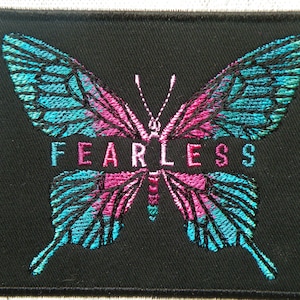 May include: Black embroidered patch with a teal and pink butterfly and the word "FEARLESS" in pink lettering.