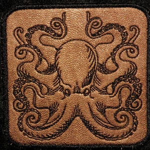 May include: A brown leather patch with a black embroidered octopus design. The octopus has eight tentacles with intricate details.