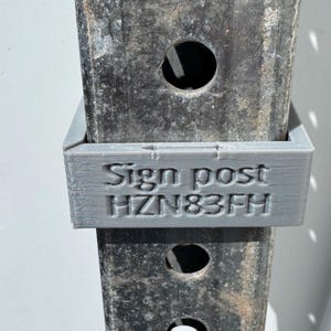 May include: A gray sign post holder is attached to a metal post. The text "Sign post" and "HZN83FH" are printed on the holder. The metal post has circular holes.