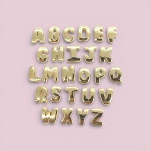 Peut inclure: Lettres de l'alphabet en ballons dorés, disposées en rangées sur un fond rose clair. Les lettres sont dans une police sans empattement et semblent gonflées. Idéal pour les décorations de fête ou les messages personnalisés.