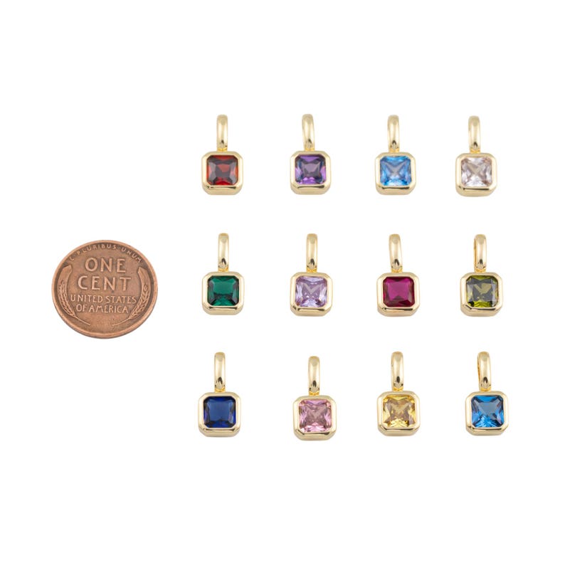 K&ouml;nnte beinhalten: Eine Sammlung goldfarbener quadratischer Anh&auml;nger mit verschiedenfarbigen Edelsteinen, darunter Rot, Lila, Blau und Gr&uuml;n. Eine Ein-Cent-M&uuml;nze dient zum Gr&ouml;&szlig;envergleich. Die Anh&auml;nger haben oben eine kleine Schlaufe zum Befestigen an einer Kette.