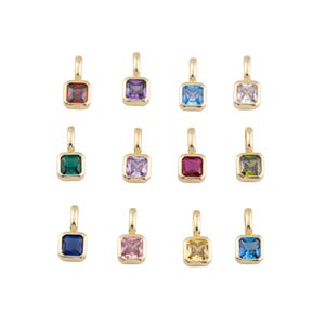 K&ouml;nnte beinhalten: Eine Sammlung von zw&ouml;lf goldfarbenen Anh&auml;ngern, jeweils mit einem quadratisch geschliffenen Edelstein in einer anderen Farbe. Die Edelsteine umfassen Rot, Lila, Blau, Klar, Gr&uuml;n, Rosa und Gelb. Jeder Anh&auml;nger hat eine kleine Schlaufe oben.