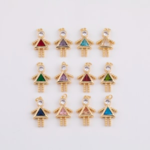 Puede incluir: Encantos de metal dorado en forma de persona estilizada, cada uno con una gema triangular en varios colores. Los amuletos tienen un pequeño lazo en la parte superior y piernas y brazos con cuentas. Las piedras preciosas incluyen rojo, morado, turquesa y verde.