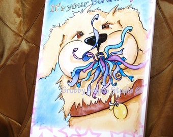 Peut inclure: Une carte de vœux rectangulaire présentant une illustration à l'aquarelle d'un chien doré au pelage touffu tenant des serpentins bleus et violets dans sa gueule. Le texte It's your Birthday! est inscrit en haut et le chien porte un collier marron.