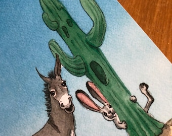 Peut inclure: Illustration à l'aquarelle d'un âne, d'un lapin et d'un cactus. L'âne est gris et souriant. Le lapin, avec des oreilles roses, regarde derrière le cactus vert. Le fond est bleu clair.
