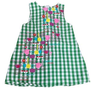 May include: A sleeveless green and white checkered dress with a whimsical kitchen-themed print. The print features colorful illustrations of cooking utensils, pots, and vegetables, with text in French. The dress has a round neckline and a flared silhouette.