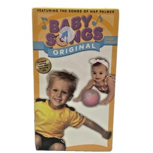 May include: A VHS tape for "Baby Songs Original" featuring the songs of Hap Palmer. The cover has a yellow background with the title in blue and purple. Images of two babies are on the front. Ages 1 and up.