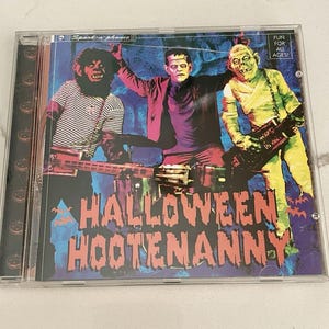 Puede incluir: Una caja de CD de plástico transparente con la portada del álbum Halloween Hootenanny. La ilustración muestra a un hombre lobo, el monstruo de Frankenstein y una momia tocando instrumentos sobre un fondo azul. El texto dice Spook-a-phonic y Fun for all ages.