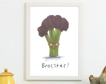 May include: A white framed print with a cartoon illustration of a purple broccoli wearing sunglasses with yellow stars. The text "Brocstar!" is written below the broccoli.