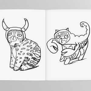 May include: A black and white line drawing of two cats wearing costumes. One cat is wearing a bull costume with horns and the other is wearing a scorpion costume with a tail.